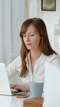 Young business woman working at desk with laptop computer in home office.