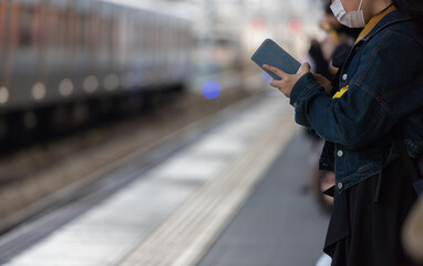 スマートフォンを弄る通勤電車を待っている人の姿