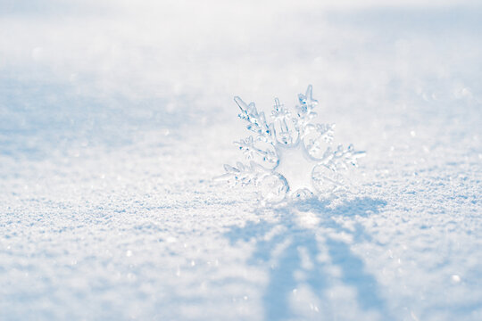 Beautiful ice crystal lies in the snow and glistens in the sun, bokeh in the blue background