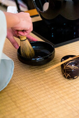 Japanese woman, tea master, Sen Rikyu, hands purifying a chasen, bamboo matcha whisk in Japanese...