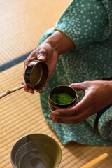 African American woman guest hands holding chashaku bamboo matcha tea spoon and opens Natsume...