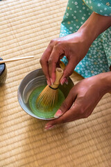 African American woman guest hand whisking matcha tea in chawan tea bowl