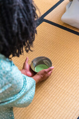 African American woman guest hands serving matcha tea in chawan tea bowl to Japanese woman, tea master, Sen Rikyu
