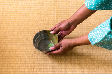African American woman guest hands serving matcha tea in chawan tea bowl to Japanese woman, tea master, Sen Rikyu © A Certain Aesthetic