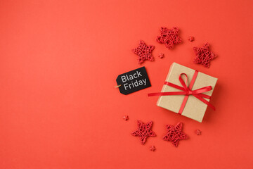 Black Friday sale banner concept, Gift box with ribbon bow and stars decoration on red background. Top view, flat lay