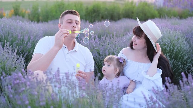 A loving father blows soap bubbles for his daughter, a happy family rests in a lavender field