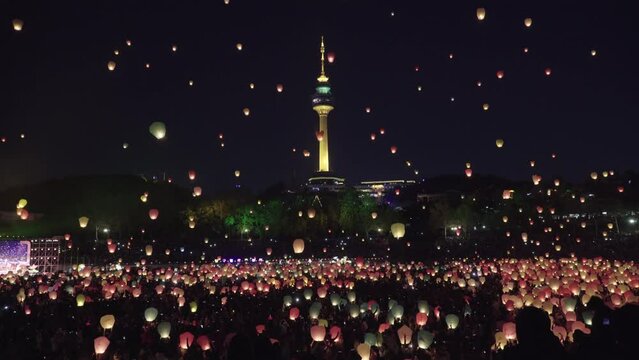 대구에서 열리는 관등축제, 하늘 위로 관등이 올라간다. 축제에 많은 사람들이 모여있고, 멀리에는 대구 83타워가 보인다