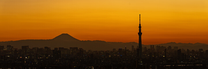 Fototapeta na wymiar Silhouette of Tokyo skytree and Mt. Fuji on orange sky background.