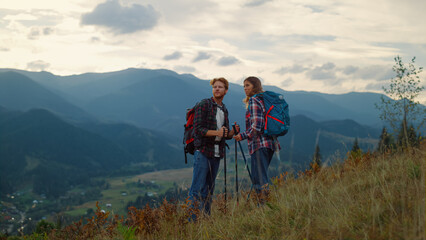 Young family hiking together on mountains nature sunset. Couple talk on hiking.