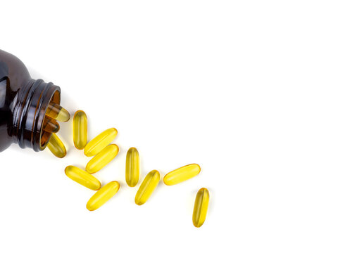 Fish Oil Capsules Spilling Out From The Bottle. Soft Gelatin Capsule Use In Pharmaceutical Manufacturing For Contain Oily Drug And Nutritional Supplement On Top View White Background.