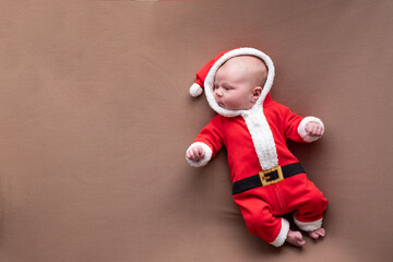 Newborn girl dressed in santa claus costume yawning being tired.