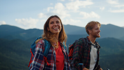 Laughing couple trekking mountains. Close up two tourists smile together outside