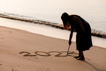 2023 Happy New Year, Young healthy woman writing 2023 on the sand beach at sunrise, health care,...