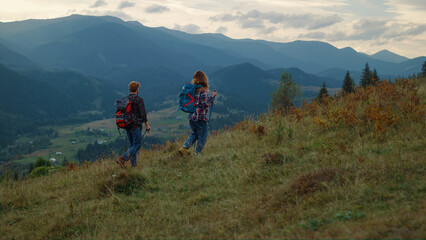 Fototapeta na wymiar Walking couple hiking mountains. Two travelers going trekking poles in nature.