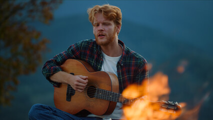 Young guitarist play music on evening nature. Closeup guy enjoy guitar in forest