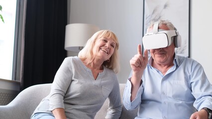 Portrait of elderly couple using virtual reality glasses while sitting in living room.