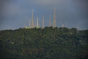 Fotobehang The radio masts and telecommunications towers at the top of Sumaré hill and above the dense, cloud-shrouded Atlantic rainforest of the Tijuca National Park, Rio de Janeiro, Brazil © Pedro