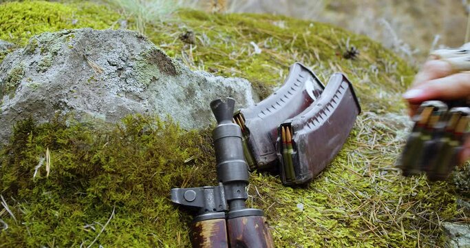 Close-up view of a male hand putting ammo on the ground.