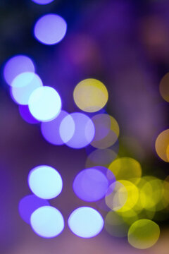 Abstract multicolored bokeh on a dark background. Beautiful vertical background with colorful bokeh on a black background