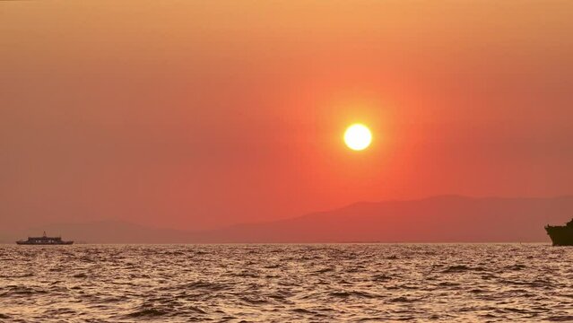 Silhouette Of Warship In The Sunset is an awesome stock video that features footage of warship and ferry passing at the red sky and sun is going down. 