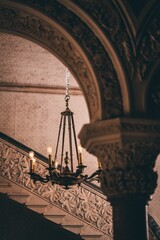 Vertical shot of antique chandelier with candles illuminating a beautiful building with columns