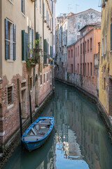 Fototapeta na wymiar Small boats parked in a typical canal in the heart of Venice, Italy