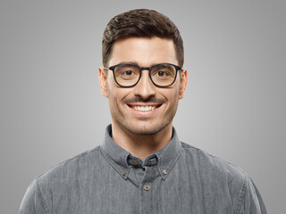 Obraz premium Portrait of young handsome businessman wearing gray shirt and glasses, feeling confident smiling
