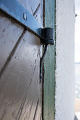 Vintage wooden door with iron hinge, outdoors. Details of architecture. 