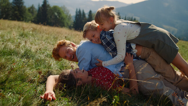 Family Piled Each Other Lying Green Grass Hill Close Up. Happy Parents Playing.