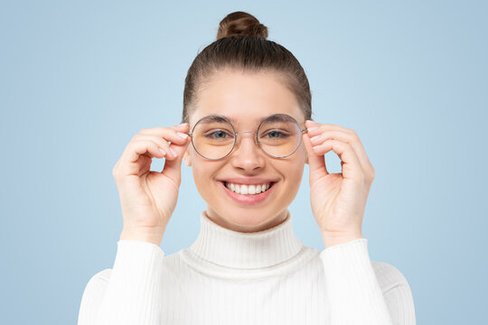 Woman holding glasses she wearing, smiling at camera, satisfied with good eyesight