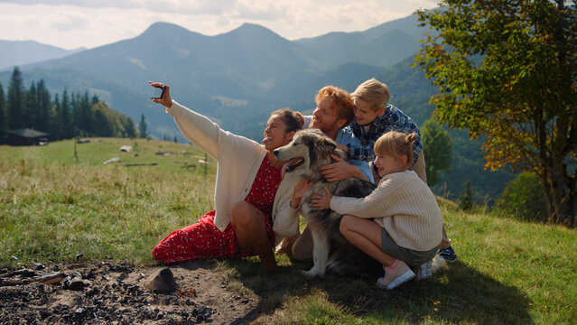 Family taking selfie mountain hill sitting with husky. Woman making happy photo.