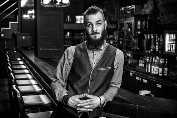 Portrait of a serious young bartender in his bar. Black and white photo.