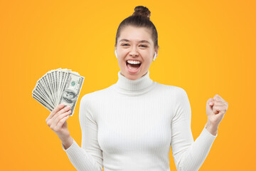Girl excited about winning cash in lottery, holding fan of 100 dollars, clenching fist and shouting
