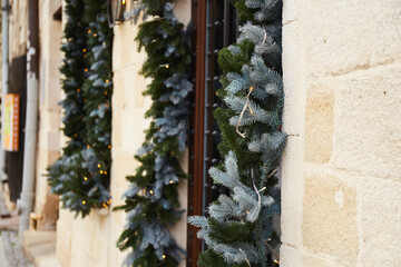Christmas Decorations. Garland Lights And Fir Branches On Window Of Cafe In European City Street