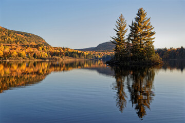 Reflections of firs of a small island at sunset on Lake Monroe, Mont-Tremblant National Park, Quebec