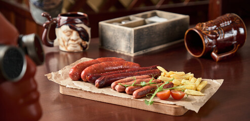 beer plate snacks sausages french fries on a wooden board on a brown table