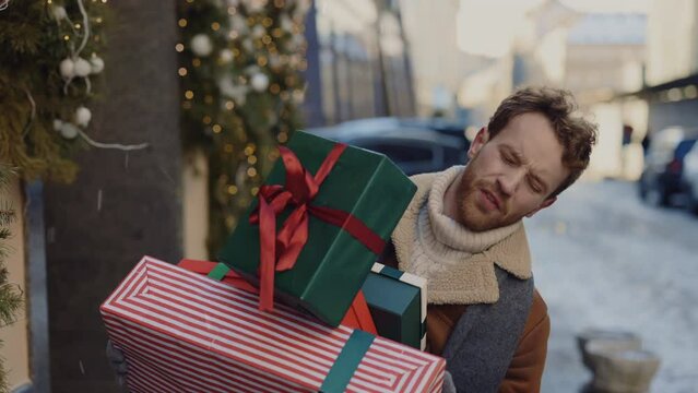 Caucasian man rushly is running home from the gift shop with many boxes and gifts fall from his hands, man feeling sad. People and christmas holidays concept