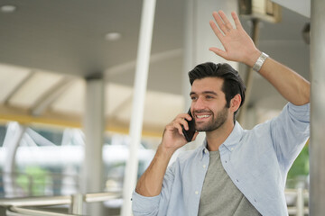 Successful young handsome businessman using phone. Handsome young businessman smartly dressed leaning on a rail while standing outdoors at the city street.