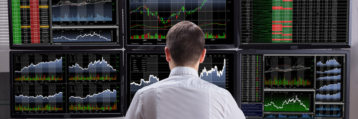 Stock Market Broker Analyzing Graphs On Computer Screens