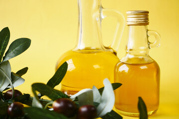 bottle of olive oil and olive leaves on yellow 