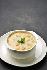 A bowl of potato soup with vegetables and meat on a dark background with copy space. Studio shot from a high angle. Vertical frame.