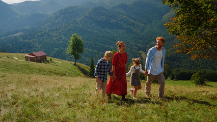 Fototapeta na wymiar Carefree family walk together on green slope. Parents enjoying nature with kids.