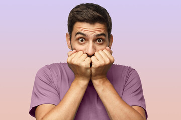 Astonished young male covering his mouth with both hands, looking shocked