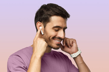 Man wearing wireless earbuds and pink tshirt, listening to favorite musical album online