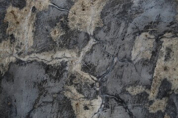 A weathered concrete wall with cracks and peeling paint, showing signs of age and decay.