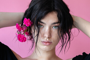 a beauty brunette woman portrait,a pink flower in the hand near face