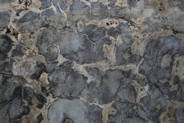 A weathered concrete wall with cracks and peeling paint, showing signs of age and decay.