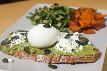 Tartine d'Avocat, Œuf Poché, Feta, Graines de Citrouille, accompagnée de Patates Douces et Salade