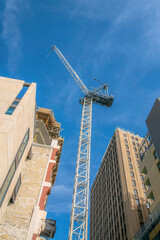 Construction tower crane in the middle of buildings in a low angle view- San Antonio, Texas