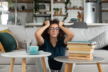 Young frustrated school girl sitting on floor with pile of books feeling sad that she need to read. Female first year college student get depressed from how much she need to study. Education concept